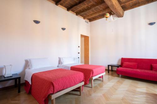 1 dormitorio con 2 camas y sofá rojo en Petroni 38 by Studio Vita, en Bolonia