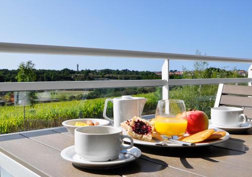 a table with a breakfast of fruit and orange juice at Golden Tulip Pornic Suites- Appart Hotel in Pornic