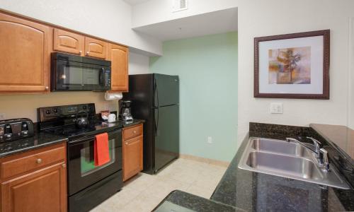 a kitchen with a stove top oven and a microwave at Lake Buena Vista Resort Village and Spa, a staySky Hotel & Resort Near Disney in Orlando