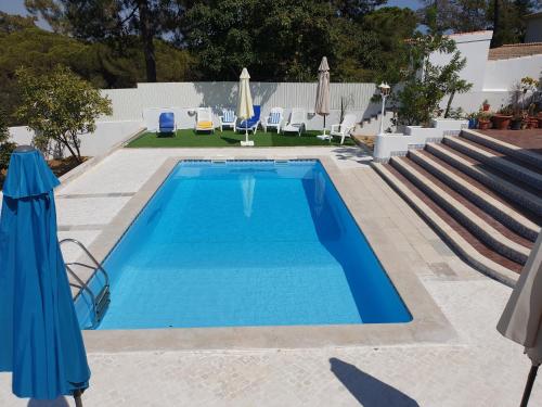 a pool with chairs and umbrellas in a resort at OceanOasis Residences Suites in Olhão