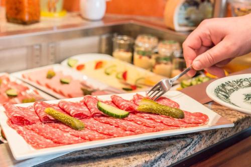 a person holding a fork and a plate of meat at Bavaria Hotel in Ingolstadt