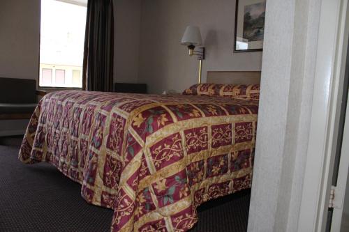 a hotel room with a bed with a colorful bedspread at Budget Host Inn Bristol in Bristol