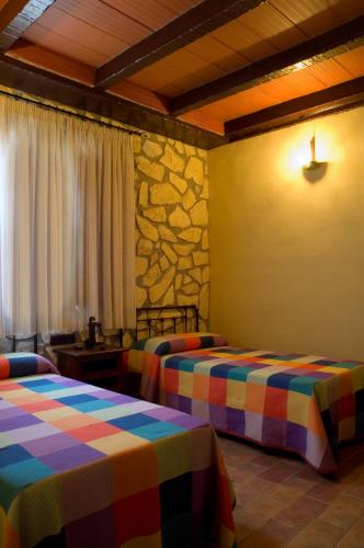a room with two beds and a stone wall at Casa Rural El Tejar Viejo in Carcabuey