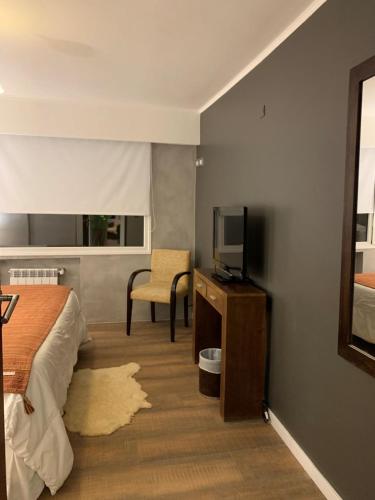 a bedroom with a bed and a tv and a chair at URBANA APARTMENTS 413 in San Carlos de Bariloche
