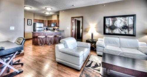 a living room with two chairs and a kitchen at Grand Inn & Residence- Grande Prairie in Grande Prairie