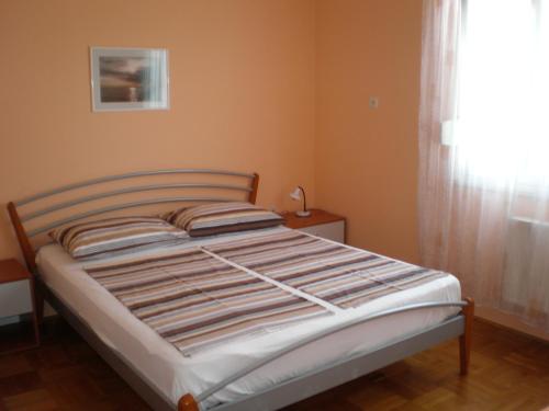 a bed in a small room with a window at Kuća Luce in Mali Lošinj