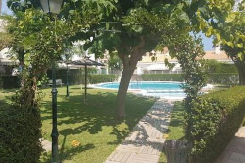 a swimming pool in a yard with trees and a building at Bungalow sol y playa in El Campello