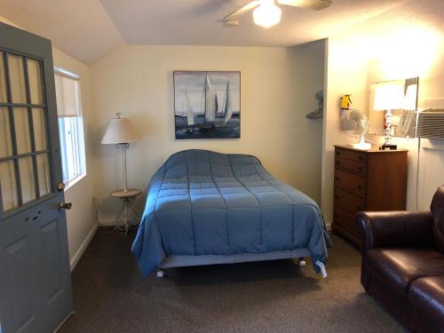 a bedroom with a blue bed and a couch at West Winds Motel & Cottages in Clayton