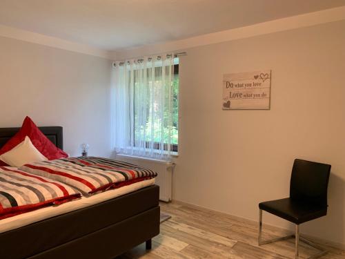 a bedroom with a bed and a chair and a window at Elbe Ferienwohnung Glückstadt in Glückstadt