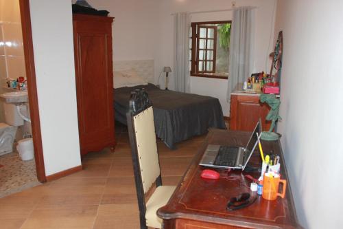 a bedroom with a desk with a laptop on it at Hostel Luz in Anchieta