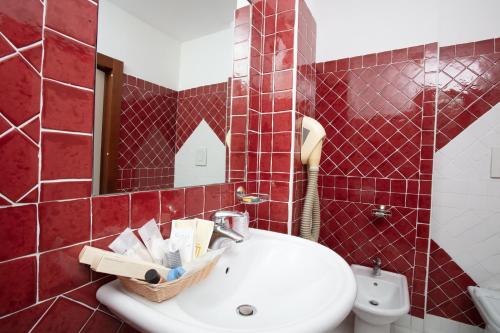 a red tiled bathroom with a sink and a mirror at Hotel Marini in Sassari