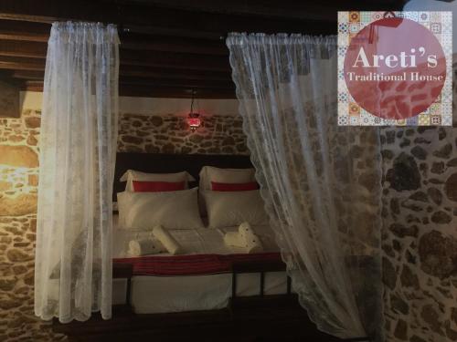 a bedroom with a bed with curtains and pillows at Areti's Traditional house in Apóllona