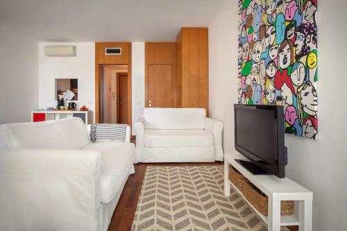 ein Wohnzimmer mit 2 weißen Sofas und einem TV in der Unterkunft LA CHIARETTO SUITE in Bardolino