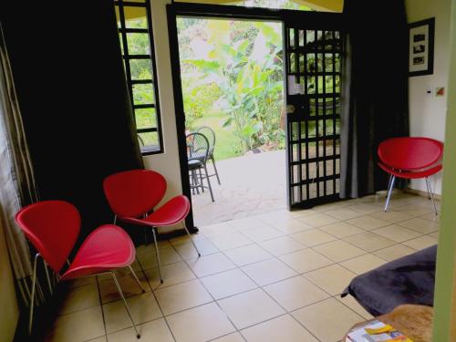 a room with red chairs and an open door at Pura Vida Hotel in Alajuela City