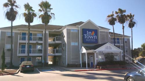 a hotel with palm trees in a parking lot at InTown Suites Extended Stay Houston TX - Cypress Station in Houston