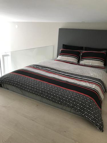 a bed with black and white sheets and pillows at Studio apartman Park Galerija in Osijek