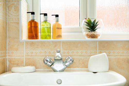 a bathroom sink with three bottles on a window ledge at Modern and Spacious Home From Home 1 mile from M1 - with Netflix, Prime Video, PS5, free parking, superfast WiFi, BBQ - Sleeps 11 - By Brightleap Apartments in Milton Keynes
