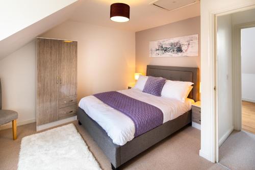 a bedroom with a large bed and a cabinet at Brightleap Apartments - Modern and Spacious Home From Home 1 mile from M1 - Netflix, Prime Video, PS5 - Sleeps 11 in Milton Keynes