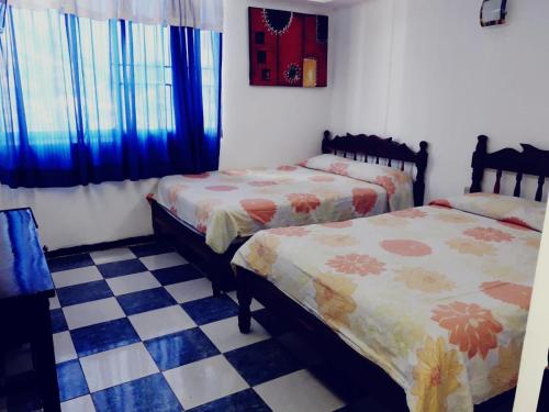 a bedroom with two beds and a checkered floor at Hotel Marina Campeche in Campeche