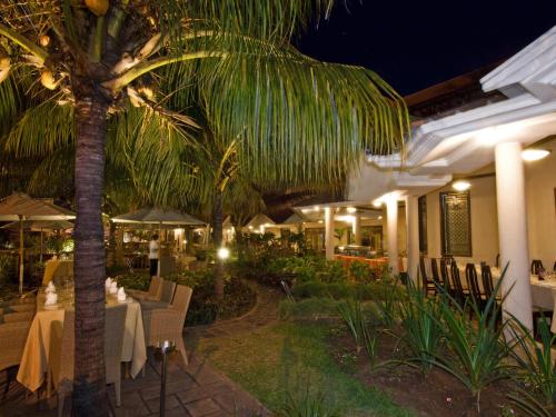 a restaurant with tables and chairs and a palm tree at Aanari Hotel & Spa- Mauritius in Flic-en-Flac