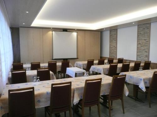 een conferentieruimte met tafels en stoelen en een scherm bij Hotel Adelboden in Wikon
