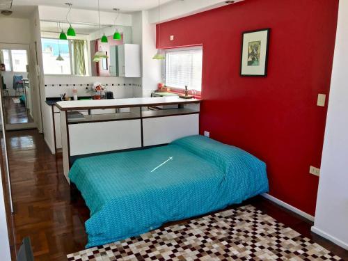 uma cozinha com paredes vermelhas e uma cama azul num quarto em Bright, open view studio in Retiro em Buenos Aires