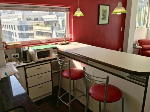 uma cozinha com um balcão com 2 bancos e um micro-ondas em Bright, open view studio in Retiro em Buenos Aires