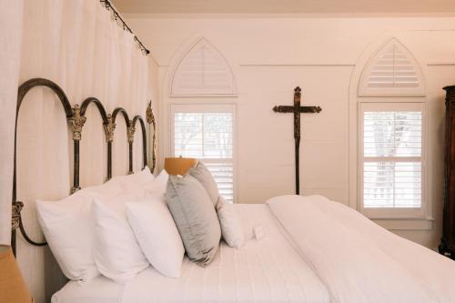 a bedroom with a bed with white pillows and a cross at The Kendall in Boerne