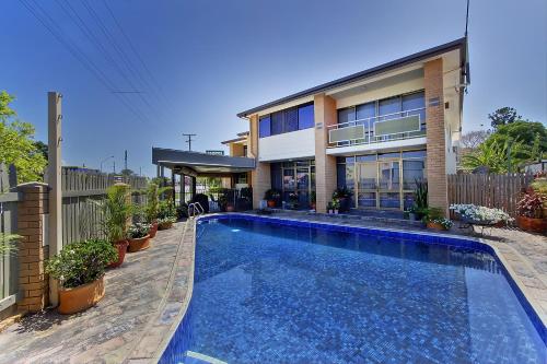 a house with a swimming pool in front of a house at Raintree Motel in Townsville