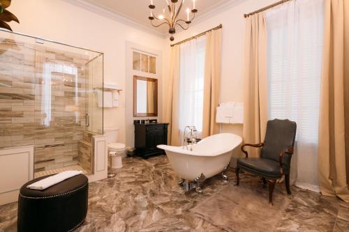 a bathroom with a bath tub and a chair and a tub at The Kendall in Boerne