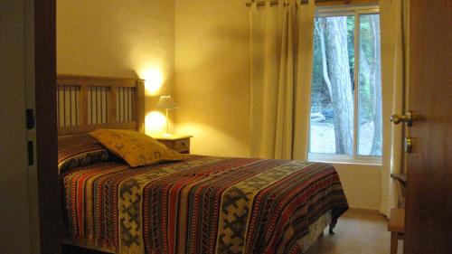 a bedroom with a bed and a window at Manantial Hostería & Cabañas in Nono