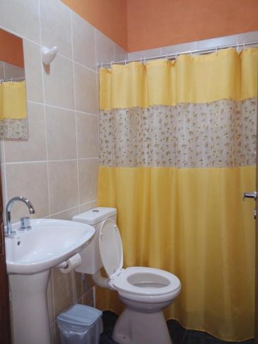 baño con aseo y cortina de ducha amarilla en Cabañas Las Bahienses en San Rafael