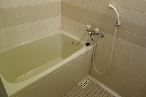 a bathroom with a bath tub with a shower at Mutsumikan in Gero