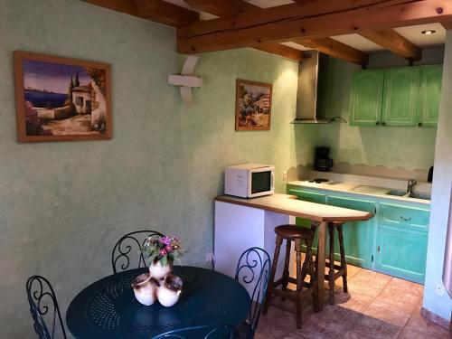 une petite cuisine avec une table et un micro-ondes dans l'établissement L'estaminet de la vallée - Le provençal, à Russ