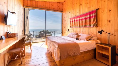 a bedroom with a bed and a desk and a window at Hotel Puerto Viejo Llico in Llico