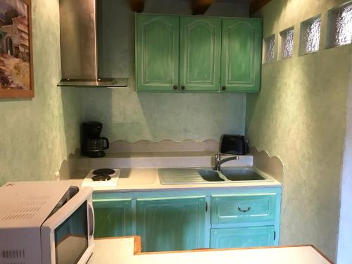 eine Küche mit grünen Schränken und einem Waschbecken in der Unterkunft L'estaminet de la vallée - Le provençal in Russ
