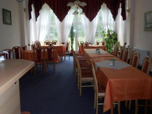 a dining room with tables and chairs and windows at Penzion u Zámku in Habartov