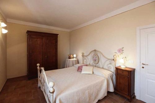 a bedroom with a white bed and a wooden cabinet at Borgo Villa Risi in Siena