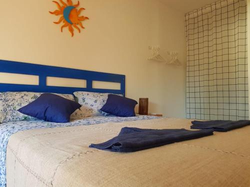 a bed with a blue head board and blue pillows at Apartamento Solar do Forte - Praia do Forte in Praia do Forte