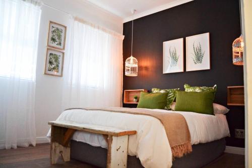a bedroom with a large bed with green pillows at Aintree Farm Cottage in Langebaan
