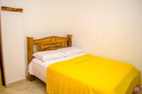 a bedroom with a bed with a yellow blanket at Hostal Casa Roma in Taganga