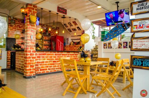 a restaurant with wooden tables and chairs and a brick wall at Hostal Casa Roma in Taganga