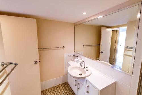 
a bathroom with a sink, mirror, and bathtub at Burgess @ Kings Beach Apartments in Caloundra
