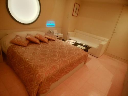 Hotel PLAISIR (Adult Only) في هيروشيما: غرفة نوم بسرير ونوافذ دائرية