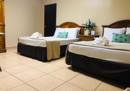 two beds in a hotel room with towels on them at Arecibo Inn in Arecibo