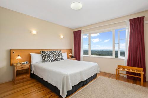 a bedroom with a bed and a large window at Waitakere Resort & Spa in Auckland