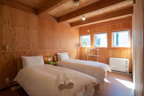 2 camas en una habitación con paredes de madera en Midori, en Niseko