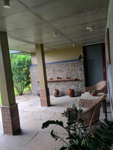 a patio with two chairs and a stone wall at Homestay Namaha in Meppādi