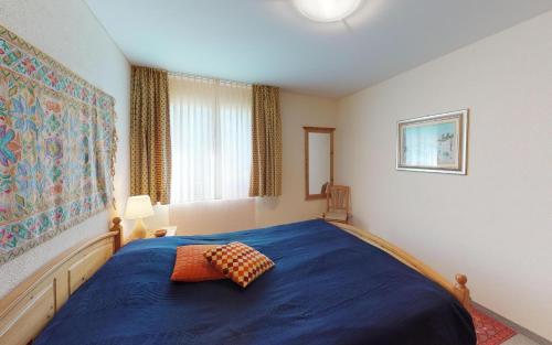 a bedroom with a blue bed and a window at Surpunt 44 in St. Moritz