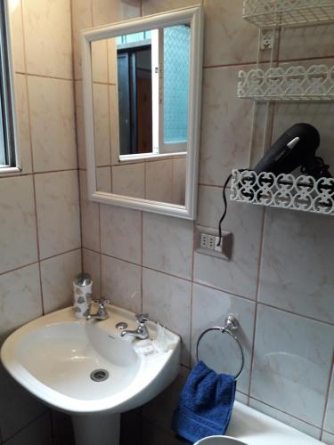 een badkamer met een wastafel, een spiegel en een toilet bij Apart-Hotel Colonia-Königsberg ESTACIONAMIENTO Deptos Completos Ubicado En El Centro De Valdivia AIRE ACONDICIONADO in Valdivia